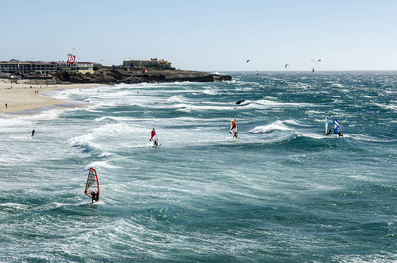 Windsurfers surfen over de branding van Praia do Guincho