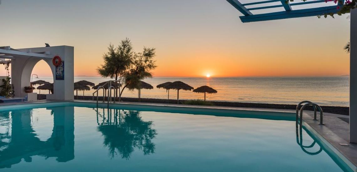 Sigalas zwembad met strandparasolletjes met zonsondergang